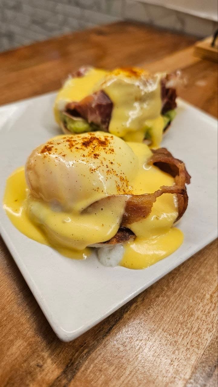 Huevos benedict de la cocina de Baristas Club servidos sobre una mesa de madera